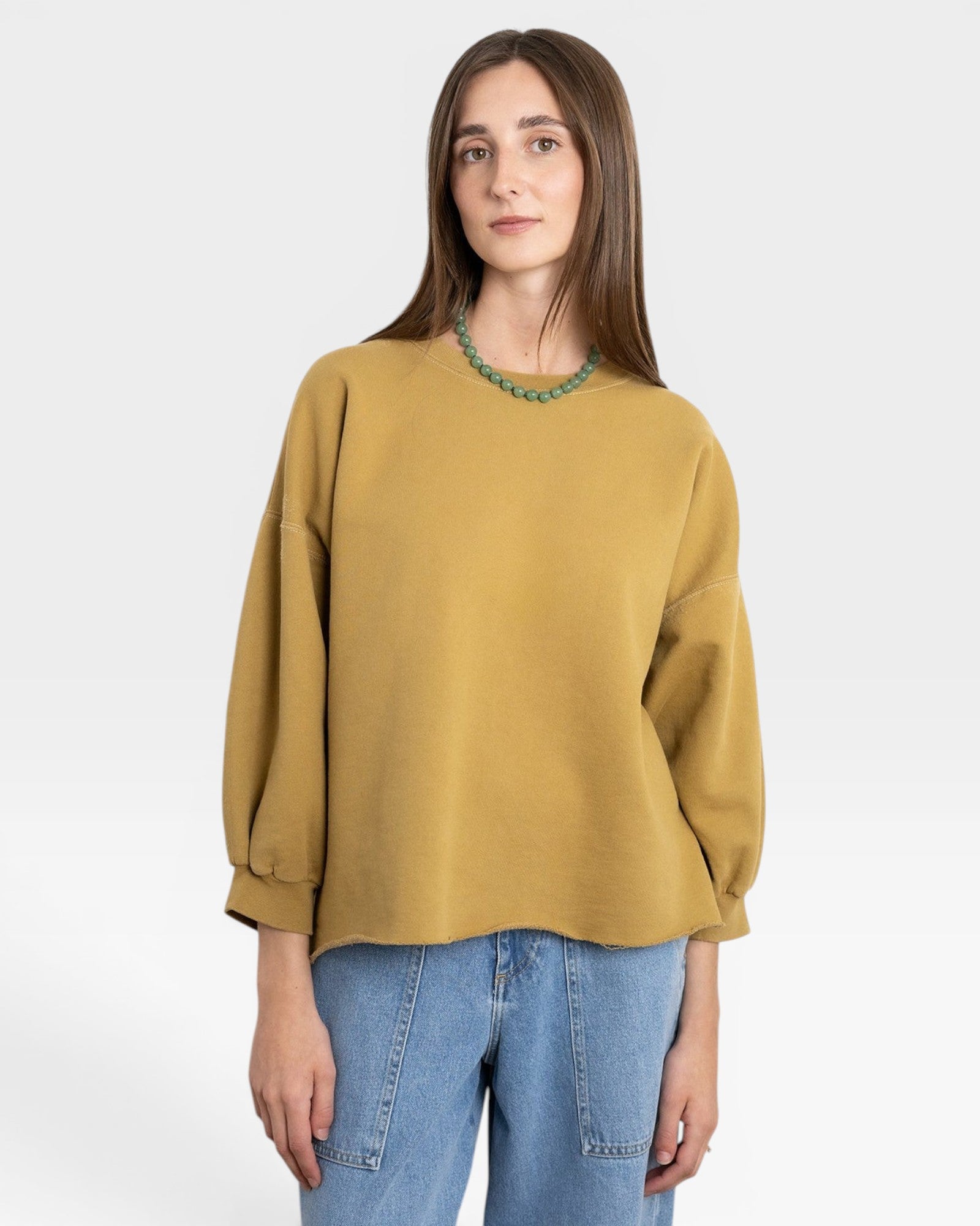 JONES + CO Fond Sweatshirt in tapenade green with raw hem, drop shoulders, and cropped sleeves.