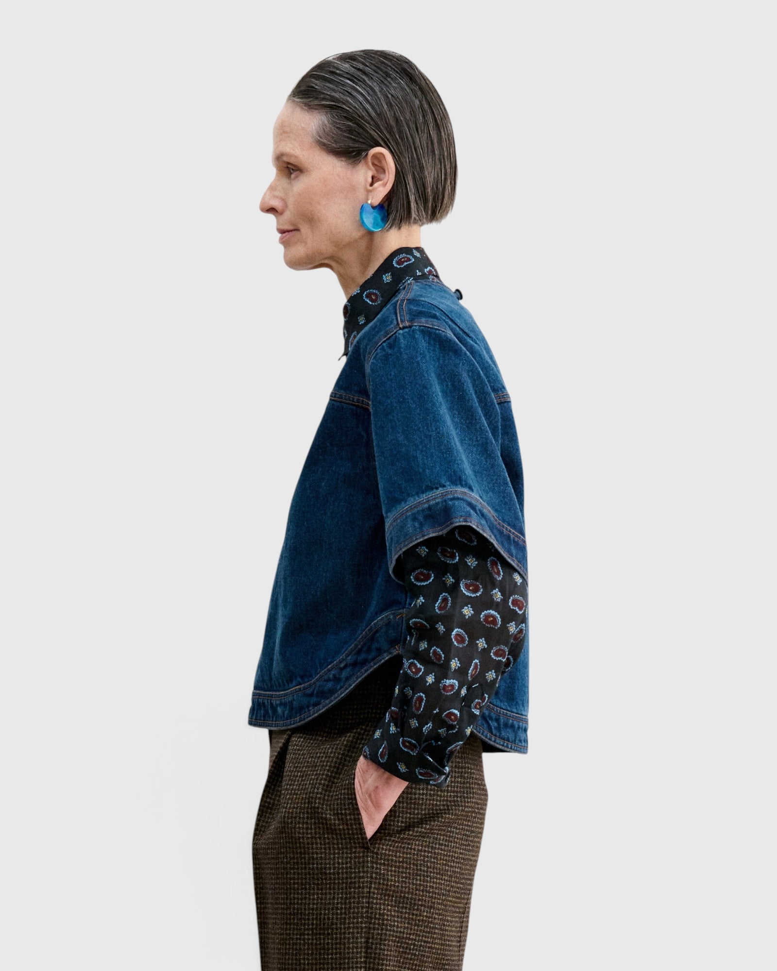 JONES + CO Fort Top in muddy indigo denim with a boxy silhouette, worn over a patterned shirt and brown trousers.