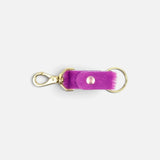 JONES + CO fuchsia cowhide keychain with gold-tone metal clasp and ring on a plain background