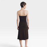JONES + CO Gaia strapless midi dress in espresso. A model with short brown hair wears the dress from behind.