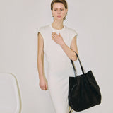 JONES + CO Scallop Tote in ganache suede held by a model wearing a white sleeveless dress against a neutral background.