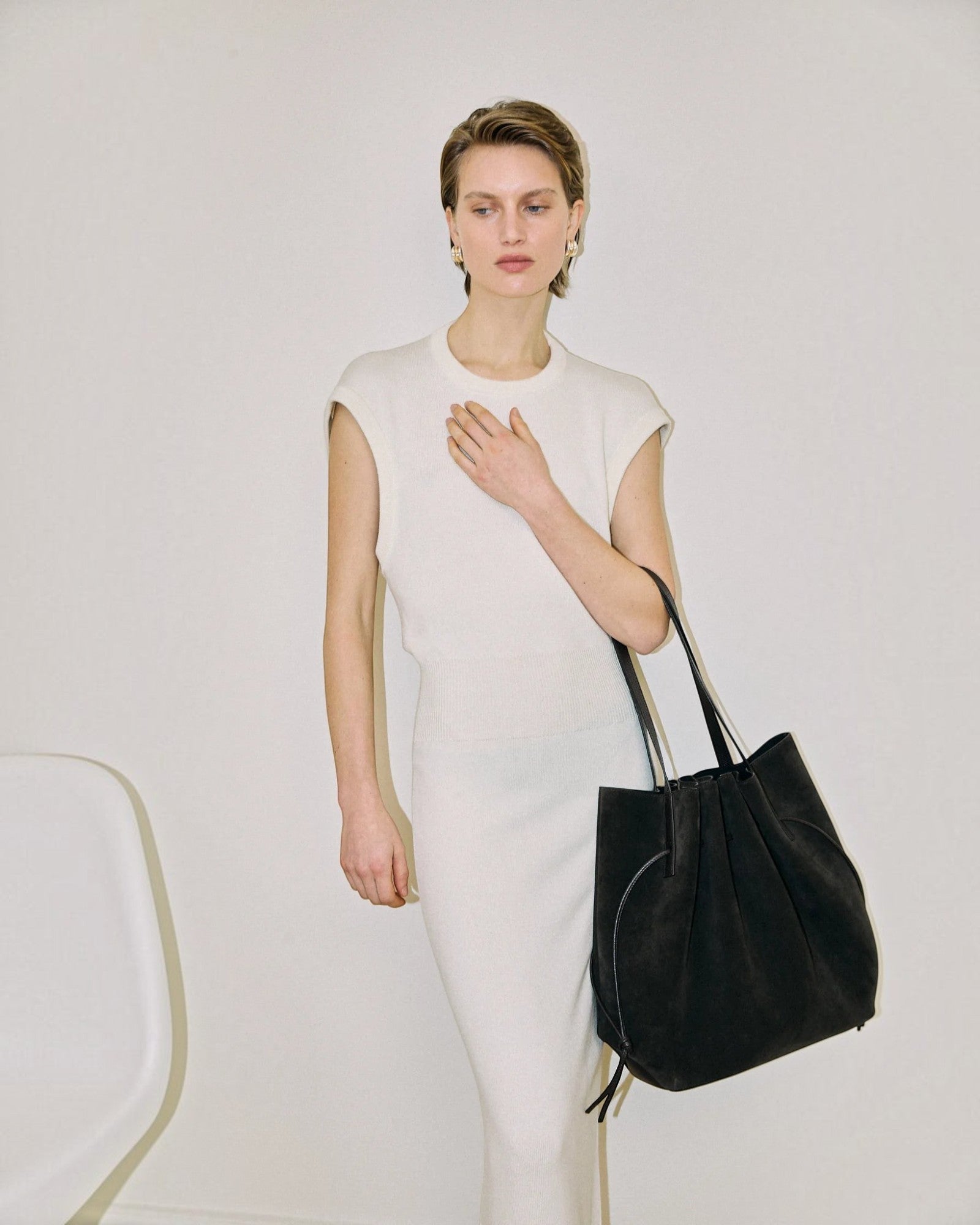 JONES + CO Scallop Tote in ganache suede held by a model wearing a white sleeveless dress against a neutral background.