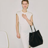 JONES + CO Scallop Tote in ganache suede held by a model wearing a white sleeveless dress against a neutral background.