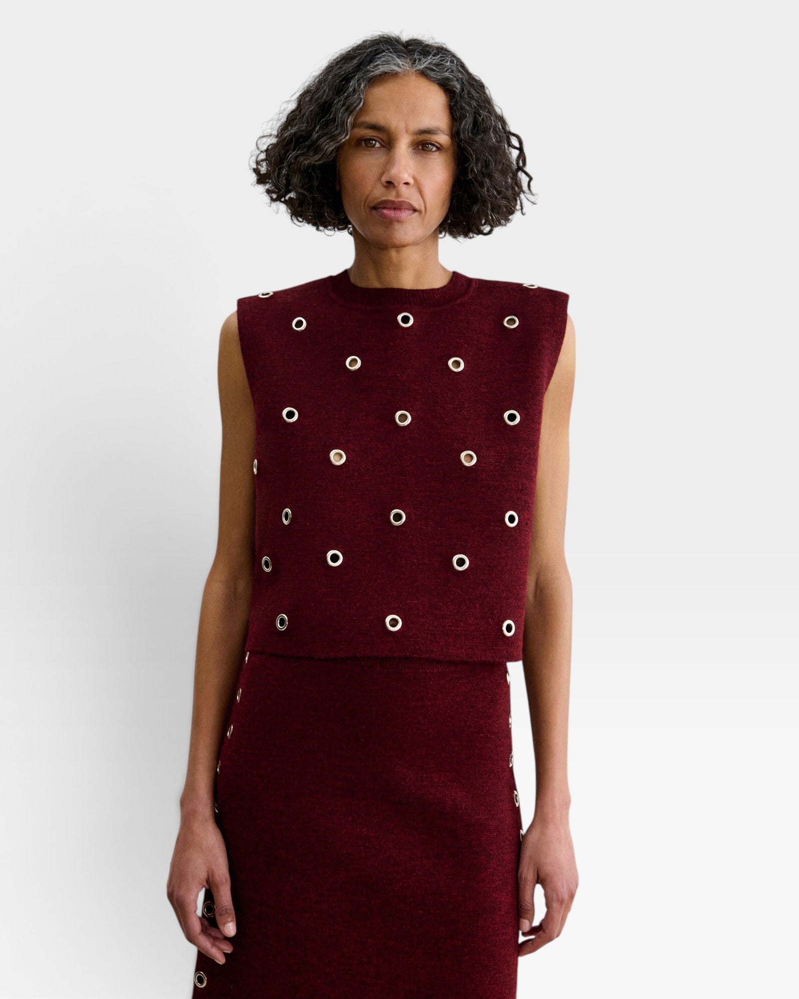 JONES + CO garnet baby alpaca knit vest with metallic eyelet details and a boxy, structured silhouette.