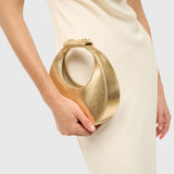 JONES + CO Good Night Moon evening bag in polished gold held in hand with a cream dress