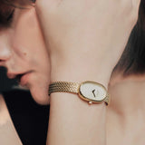 JONES + CO Jane Small Tethered watch with gold oval case, champagne mother of pearl dial, and woven mesh bracelet.