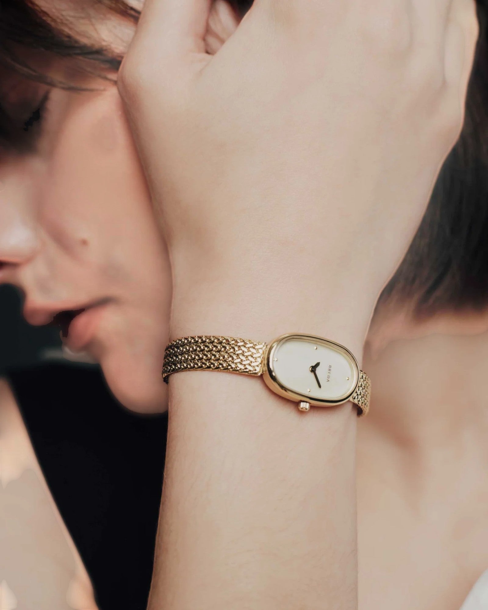 JONES + CO Jane Small Tethered watch with gold oval case, champagne mother of pearl dial, and woven mesh bracelet.