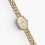 JONES + CO Jane Small watch with an 18mm gold oval case, champagne mother of pearl dial, and woven gold mesh bracelet.