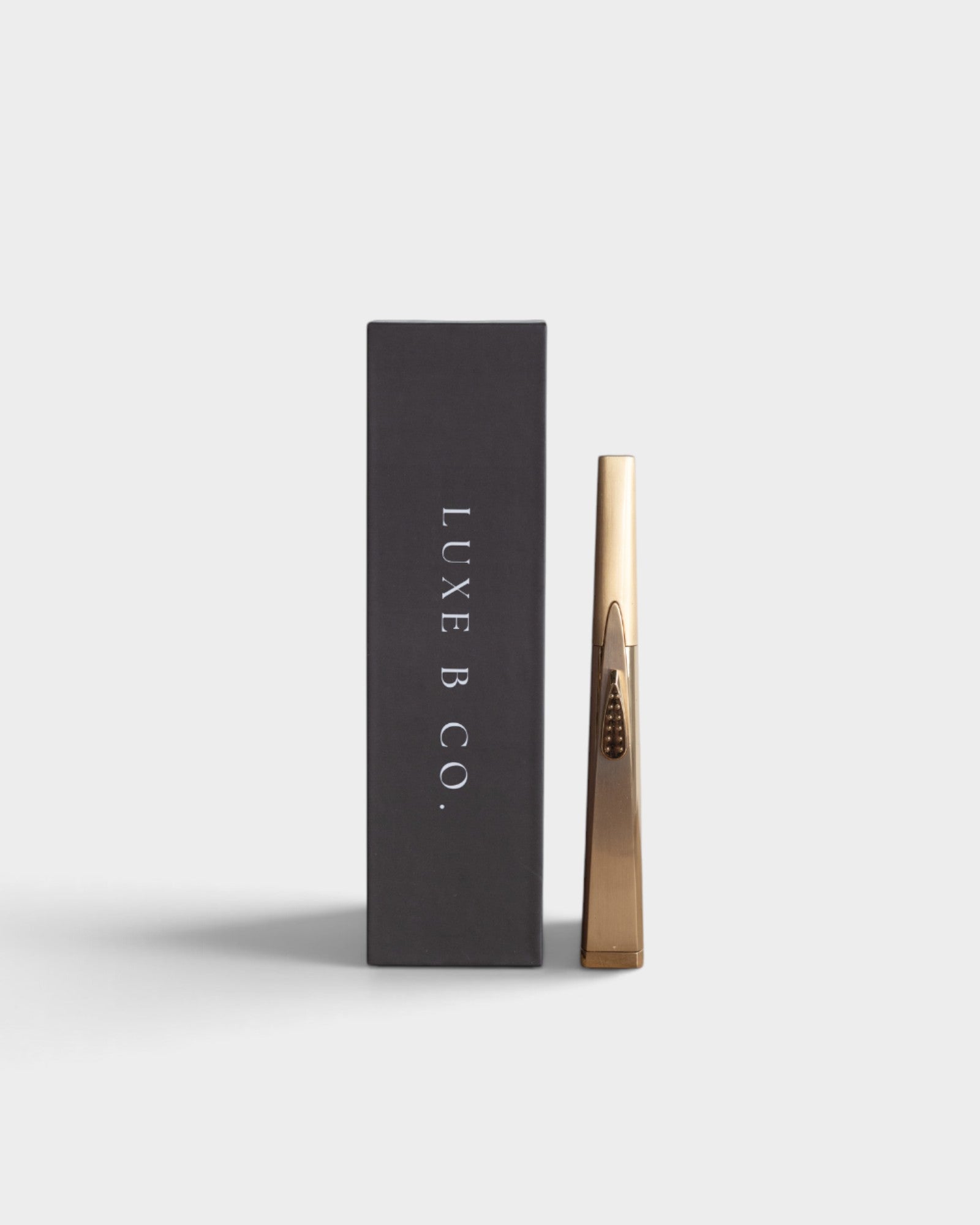 JONES + CO gold rechargeable USB arc lighter standing next to its sleek black presentation box