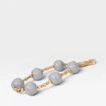 JONES + CO grey ceramic and wood beaded hanging wall art with tassel detail.