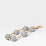 JONES + CO grey ceramic and wood beaded hanging wall art with tassel detail.