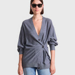 JONES + CO grey lightweight tissue cardigan with a side-cinched button detail worn by a woman in sunglasses.