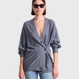 JONES + CO grey lightweight tissue cardigan with a side-cinched button detail worn by a woman in sunglasses.