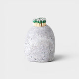 JONES + CO hand-drilled grey beach stone match striker filled with green-tipped matches on a neutral background