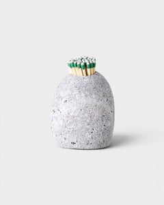JONES + CO hand-drilled grey beach stone match striker filled with green-tipped matches on a neutral background