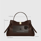 JONES + CO Gyoza pouch in Sierra embossed brown leather with a gold clasp and iPhone 16 Pro Max for size reference.