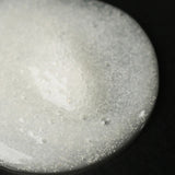 JONES + CO The Hand Exfoliant with fine perlite and rambutan, clear gel with white beads and bubbles.