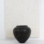 JONES + CO handthrown black ceramic vase with a rounded sculptural shape, displayed against a textured white canvas.