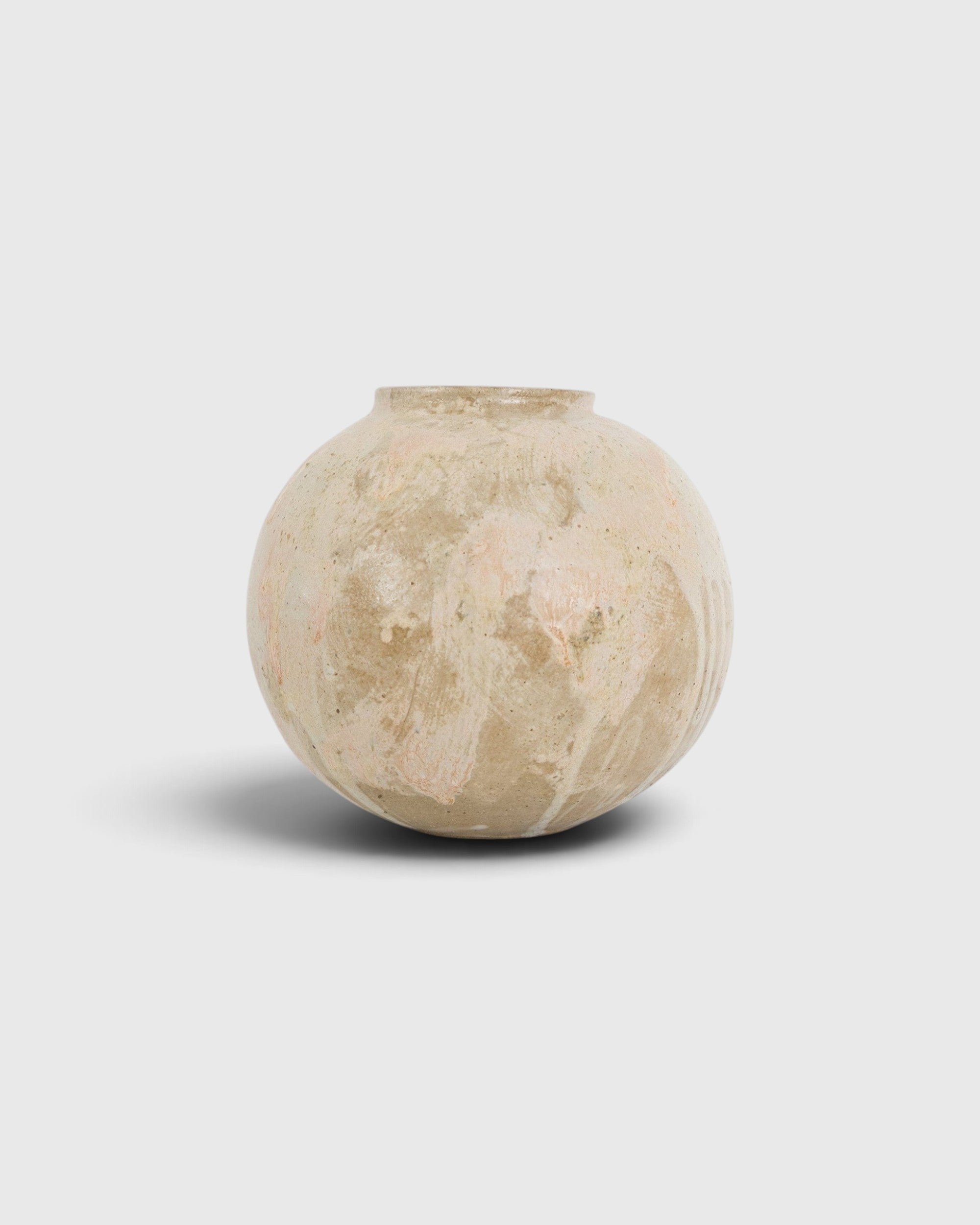 JONES + CO handthrown ceramic vase with a round, sculptural shape and textured beige and soft pink glaze finish.