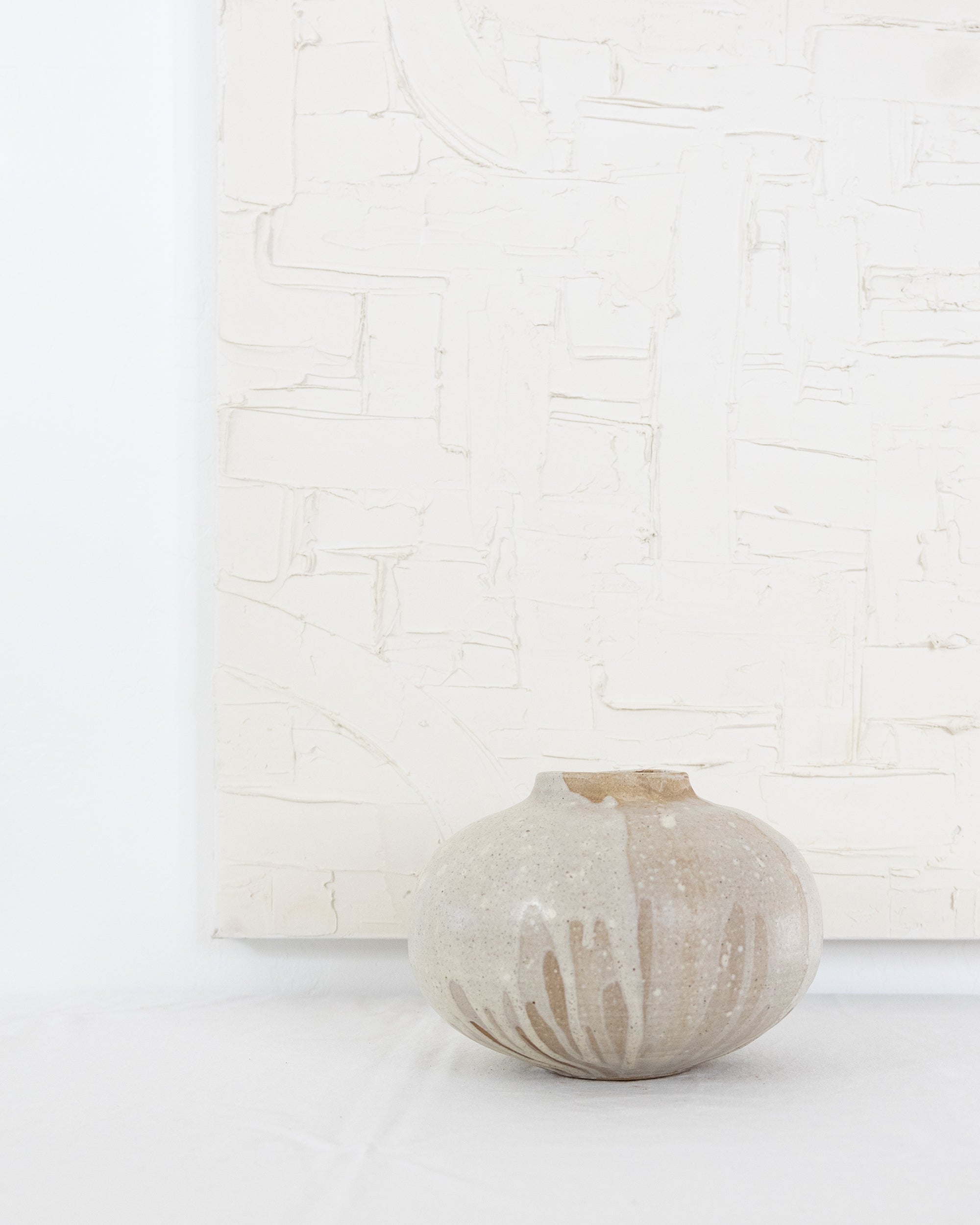 JONES + CO handthrown ceramic Vase No. 5 with a speckled beige glaze and organic rounded shape on a white surface.
