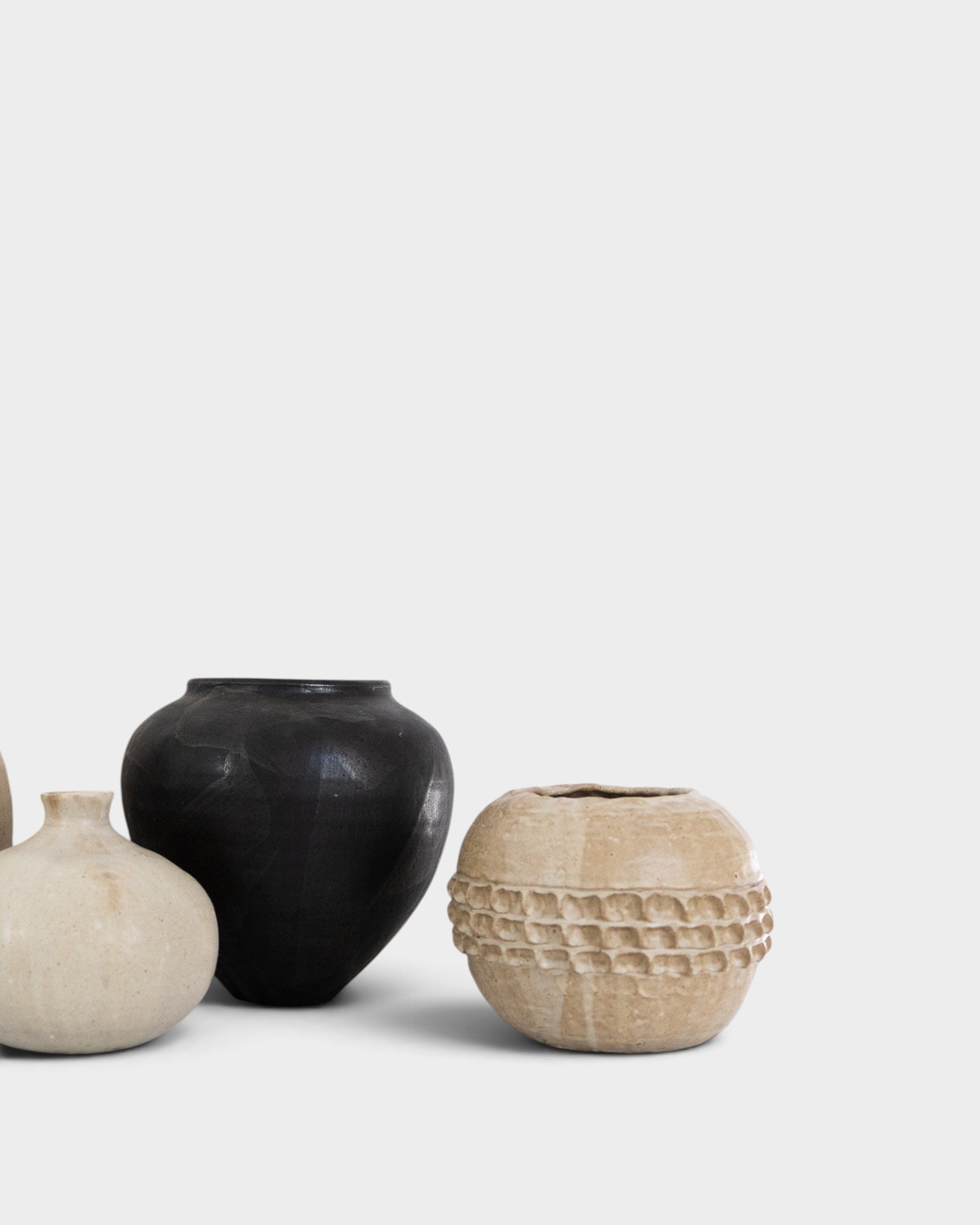JONES + CO handthrown ceramic vases in black and beige with textured patterns on a white background