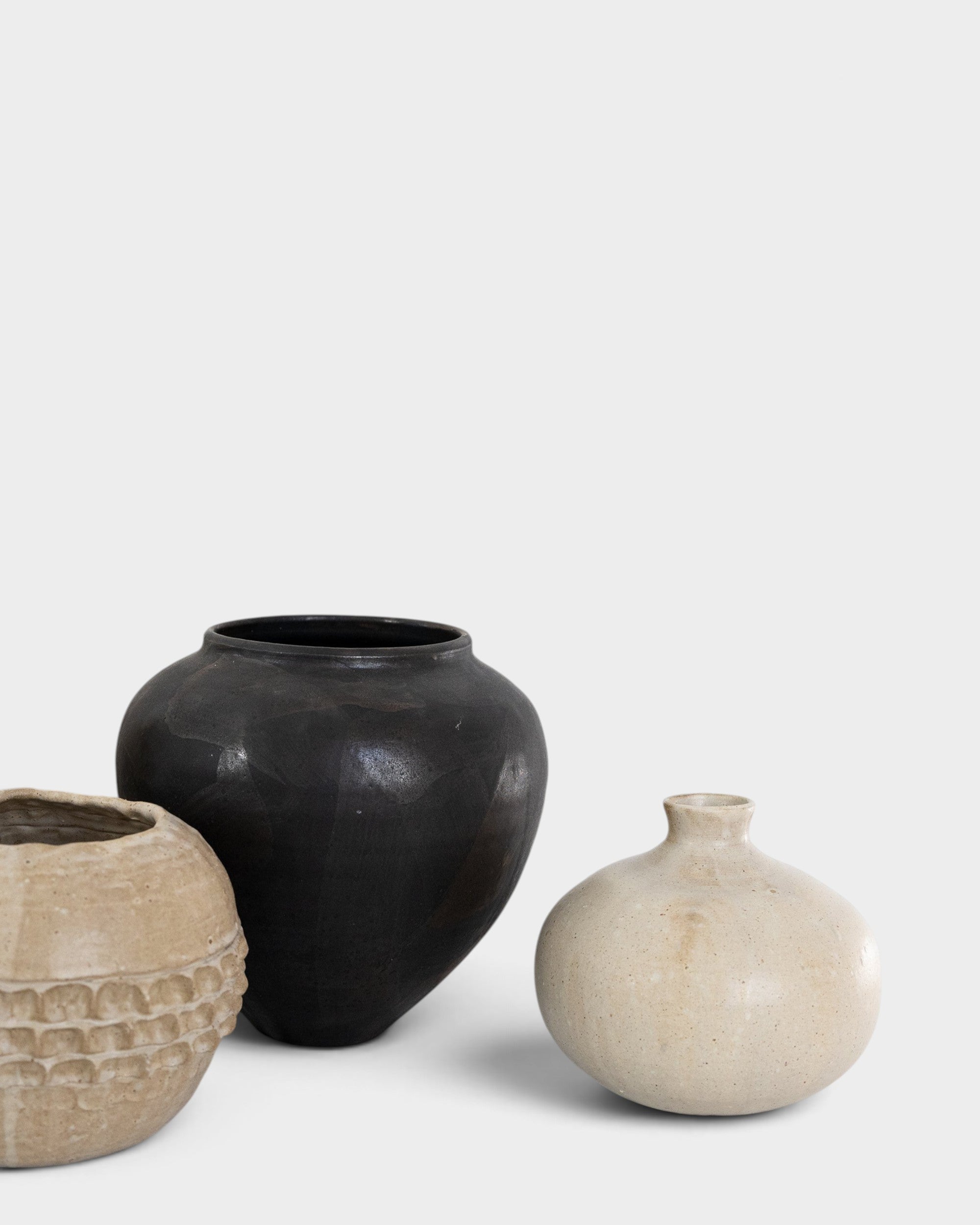 JONES + CO handthrown ceramic vases in black and cream, featuring unique textures and sculptural silhouettes.