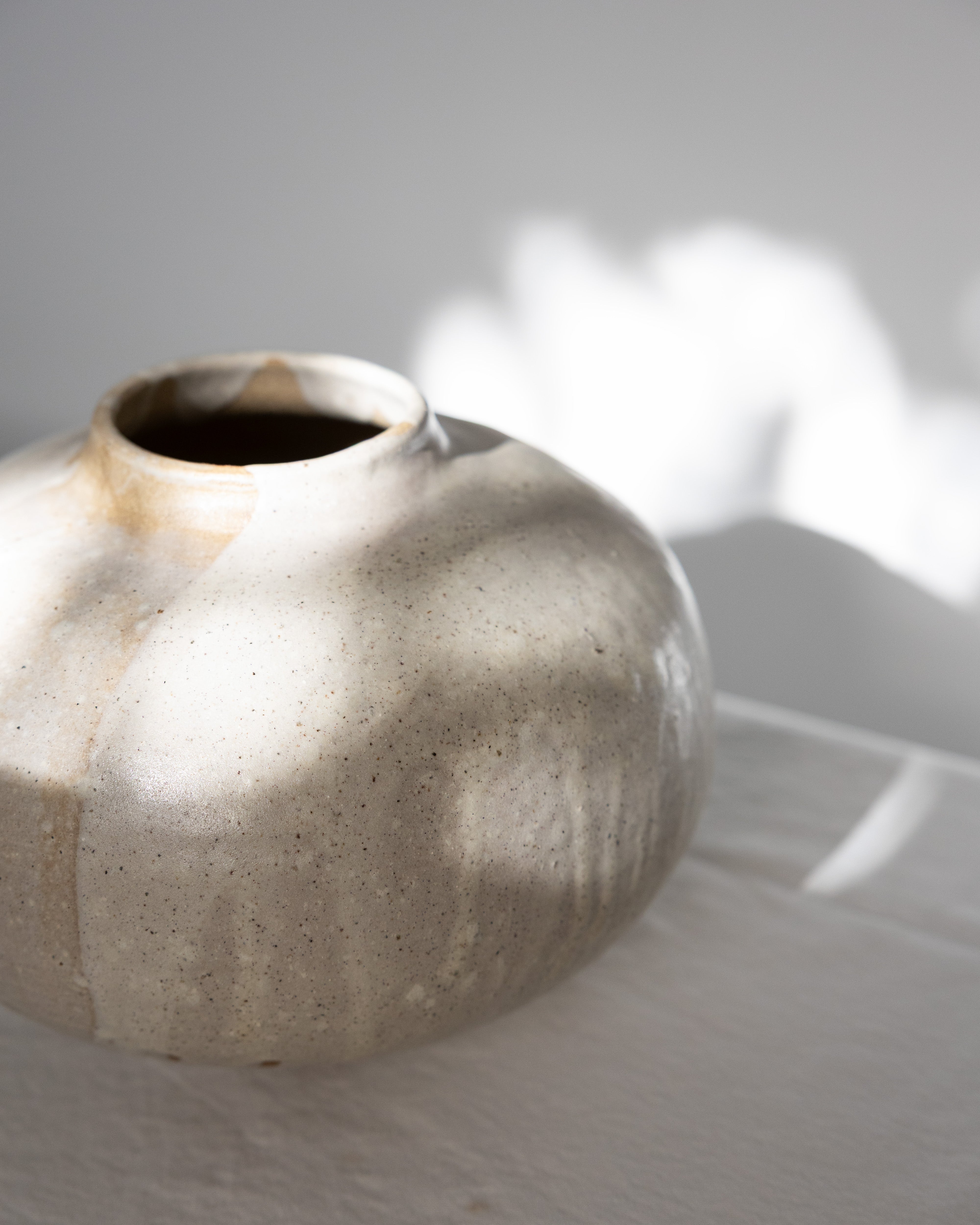 JONES + CO handthrown ceramic vase with a speckled beige glaze and organic round shape on a white surface.