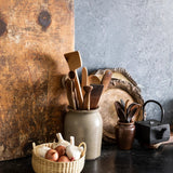 JONES + CO handwoven natural junco petite basket with handles, holding onions and garlic.