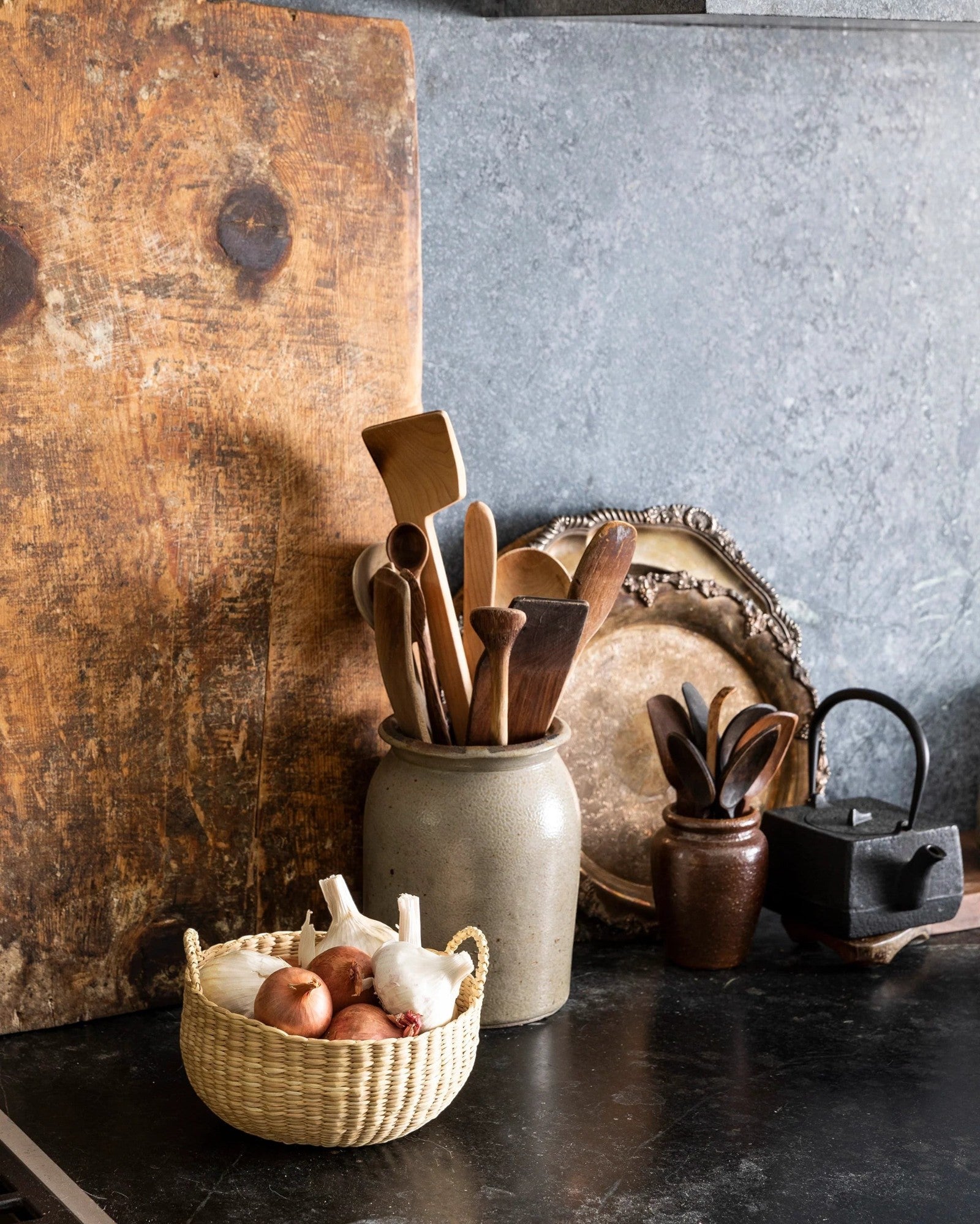 JONES + CO handwoven natural junco petite basket with handles, holding onions and garlic.