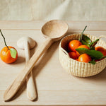 JONES + CO handwoven natural junco petite basket filled with clementines, next to wooden spoons.
