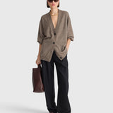 JONES + CO hazelnut cashmere-silk V-neck cardigan with drop shoulders worn by a model with black trousers and a bag