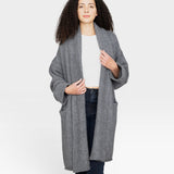 Model wearing a JONES + CO heather grey baby alpaca sweater coat with dropped shoulders and front pockets.