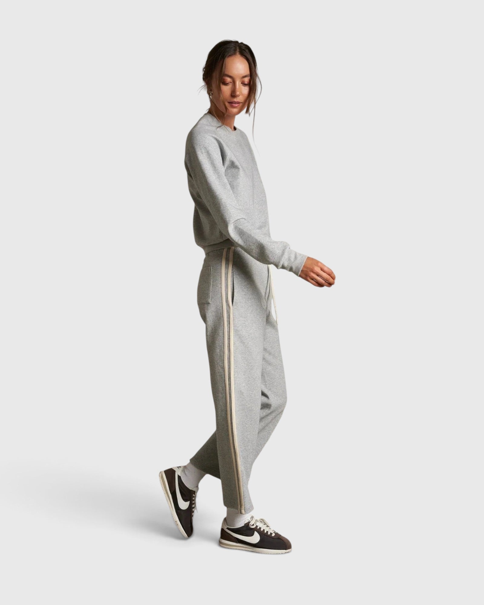 Model wearing JONES + CO heather grey cotton fleece track pants with ivory side stripes and drawstring waist
