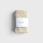JONES + CO exfoliating shower mitt made from textured cream hemp and cotton fibers with a paper product label