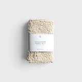 JONES + CO exfoliating shower mitt made from textured cream hemp and cotton fibers with a paper product label
