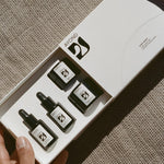 JONES + CO High West Discovery Set featuring four small dark glass bottles with dropper and cap tops, containing skincare serums and balms.