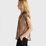 JONES + CO Hildra sleeveless bronze blouse in fluid laminated fabric with a V-neck and kimono shoulder, side view.