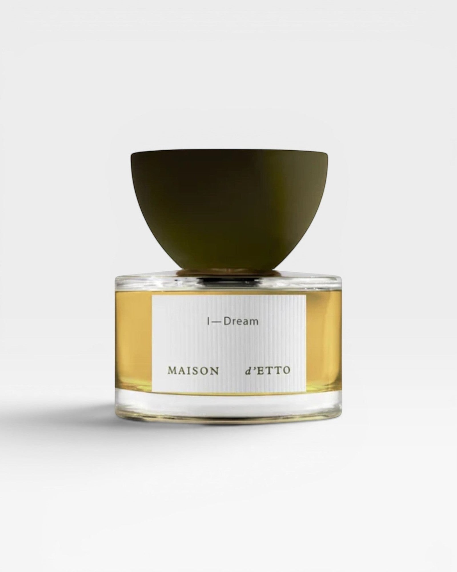 JONES + CO I-Dream Eau de Parfum in a clear glass bottle with a dark olive green cap. The golden liquid is visible.