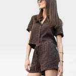 JONES + CO Ida Linen Short in chestnut brown, featuring a drawstring waist and relaxed fit. Model wears glasses.