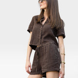 JONES + CO Ida Linen Short in chestnut brown, featuring a drawstring waist and relaxed fit. Model wears glasses.