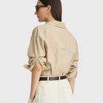 JONES + CO Isolde button-down shirt in sand and blue stripe with dropped shoulders and rolled sleeves, back view.