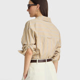 JONES + CO Isolde button-down shirt in sand and blue stripe with dropped shoulders and rolled sleeves, back view.