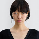 JONES + CO Rachel Comey ivory acrylic and brass draped baguette drop earrings worn by a model.