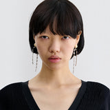 JONES + CO Rachel Comey ivory acrylic and brass draped baguette drop earrings worn by a model.