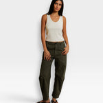 Model wearing a JONES + CO bright ivory ribbed cotton tank top with a scoop neckline paired with olive green pants.