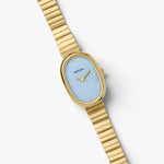 JONES + CO Jane watch with a 23mm oval gold case, sky blue mother-of-pearl dial, and gold-plated link bracelet.