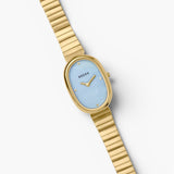 JONES + CO Jane watch with a 23mm oval gold case, sky blue mother-of-pearl dial, and gold-plated link bracelet.