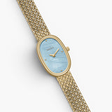 JONES + CO Jane Small watch with a gold oval case, sky blue mother of pearl dial, and woven gold mesh bracelet.