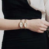 JONES + CO Jane Small Tethered watch in gold with a champagne mother of pearl dial and woven mesh bracelet on a wrist