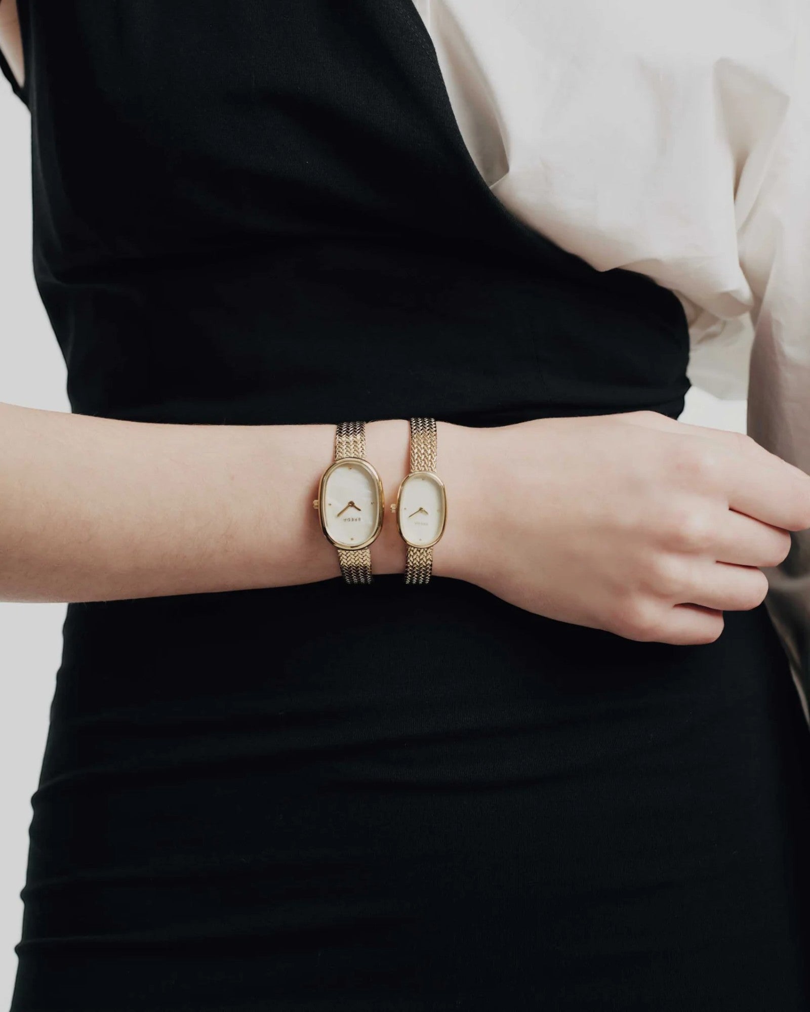 JONES + CO Jane Small Tethered watch in gold with a champagne mother of pearl dial and woven mesh bracelet on a wrist